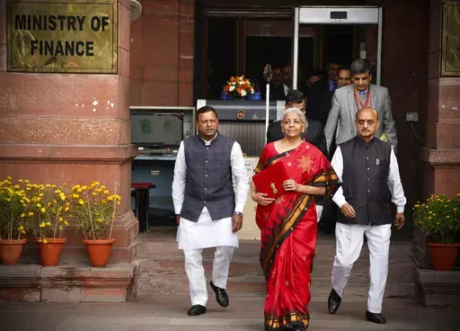 Indian Finance Minister Nirmala Sitharaman, in red, leaves her office for President's house before presenting the federal budget for the financial year 2023-24 in the Parliament in New Delhi, India, Wednesday, Feb. 1 2023. (AP Photo/Manish Swarup)