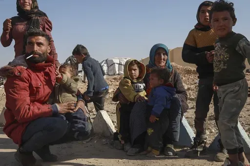 Internally displaced people sit in a camp in Tabqa city, Raqqa governorate, northern Syria, on Wednesday, Dec. 4, 2024. Thousands of Kurdish families displaced from Aleppo and Tel Rifaat have ended up in temporary shelters and on the streets in Kurdish-controlled areas of Tabqa city. (AP Photo/Hogir El Abdo)