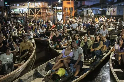 Spectators watch a film from boats during the Muyuna Floating Film Festival, showcasing films from countries with tropical forests, in the Belen neighborhood of Iquitos, Peru, on Sunday, May 26, 2024. (AP Photo/Rodrigo Abd)