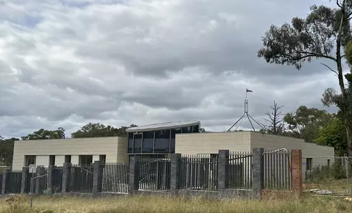 THIS CORRECTS THE PHOTOGRAPHER'S NAME TO MCGUIRK - The Australian flag flies on Parliament House, seen behind an unoccupied building on the grounds of a proposed new Russian embassy near the Australian Parliament in Canberra, Feb. 28, 2023. Australia's House of Representatives passed legislation Thursday, June 15, 2023, to prevent Russia from building a new embassy near Parliament House on security grounds. (AP Photo/Rod McGuirk)