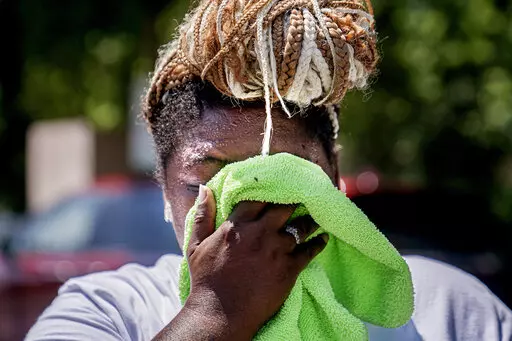 Nicole Brown wipes sweat from her face while setting up her beverage stand near the National Mall on July 22, 2022, in Washington. What's considered officially “dangerous heat” in coming decades will likely hit much of the world at least three times more often as climate change worsens, according to a new study. (AP Photo/Nathan Howard, File)