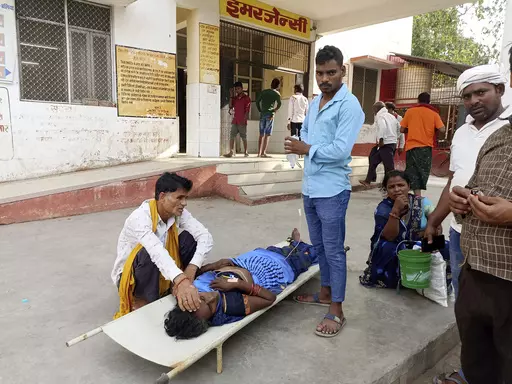 Relatives attend to a patient lying on a stretcher in the premises of a hospital in Ballia district, in northern Uttar Pradesh state, India, Sunday, June 18, 2023. Swaths of two of India's most populous states are under a grip of sever heat leaving dozens of people dead in several days as authorities issue a warning to residents over 60 and others with ailments to stay indoors during the daytime. (AP Photo)