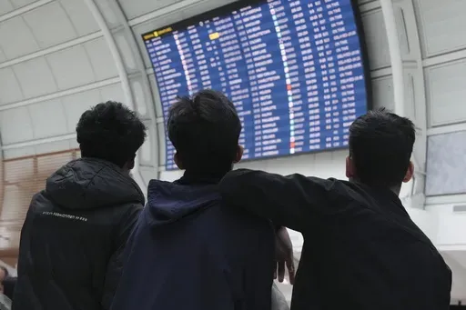 Passengers look up at the departure board as they wait due to a global technology outage at Toronto Pearson Airport, on Friday, July 19, 2024. (Chris Young/The Canadian Press via AP)