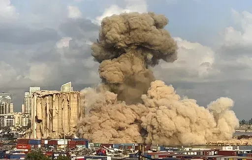 This image from a video, shows smoke and dust rising from collapsing silos damaged during the August 2020 massive explosion in the port, in Beirut, Lebanon, Tuesday, Aug. 23, 2022. The ruins of the Beirut Port silos' northern block that withstood a devastating port explosion two years ago has collapsed. The smoldering structure fell over on Tuesday morning into a cloud of dust, leaving the southern block standing next to a pile of charred ruins. (AP Photo/Lujain Jo)