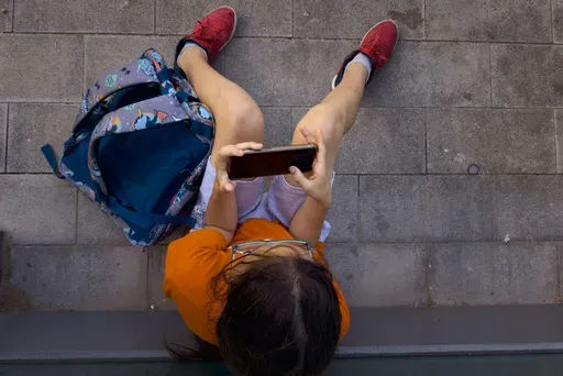 A 11-year-old boy plays with his father's phone outside school in Barcelona, Spain, Monday, June 17, 2024. (AP Photo/Emilio Morenatti, File)