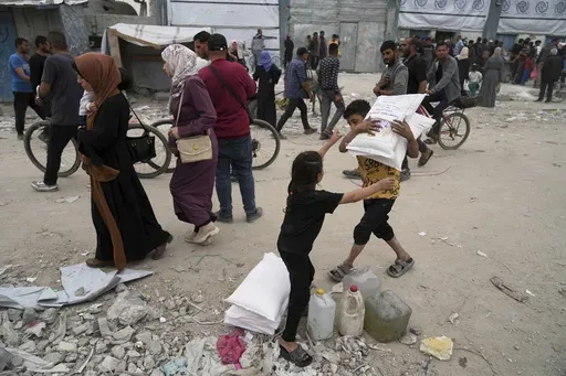 Palestinians receive bags of flour and other humanitarian aid distributed by UNRWA, the U.N. agency helping Palestinian refugees in Jabaliya, Gaza Strip on Tuesday, April 1, 2025. (AP Photo/Jehad Alshrafi)