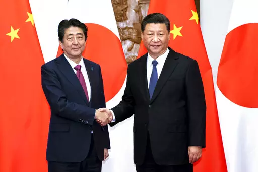 In this photo released by Xinhua News Agency, Japanese Prime Minister Shinzo Abe, left, shakes hands with Chinese President Xi Jinping as they pose for photographers before a meeting at the Diaoyutai State Guesthouse in Beijing on Oct. 26, 2018. Thursday, Sept. 29, 2022, marks the 50th anniversary of the historic communique that former Japanese Prime Minister Kakuei Tanaka signed with former Chinese Premier Zhou Enlai. (Li Tao/Xinhua via AP, File)