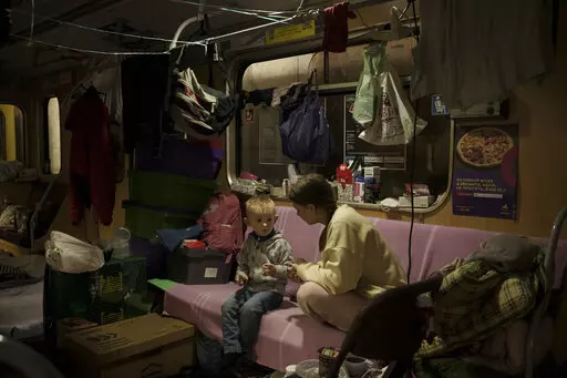 People sit inside a subway car, parked in a station being used as a bomb shelter, as Russian attacks continue in Kharkiv, Ukraine, Friday, March 25, 2022. (AP Photo/Felipe Dana)