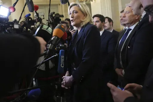 French far-right leader Marine Le Pen, center, answers reporters at the National Assembly and confirmed the National Rally party will vote against Prime Minister Michel Barnier in an upcoming no-confidence vote, Monday, Dec. 2, 2024 in Paris. (AP Photo/Michel Euler)