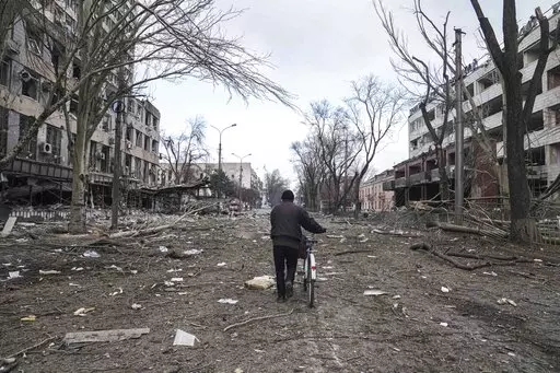 A man walks with a bicycle in a street damaged by shelling in Mariupol, Ukraine, March 10, 2022. In talks between Russia and Ukraine toward a possible cease-fire after three weeks of intense fighting, negotiators are exploring prospects of possible “neutrality” for Ukraine. (AP Photo/Evgeniy Maloletka, File)