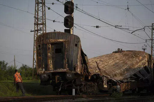 A railway worker looks at a heavily damaged train after a Russian attack on a train station Wednesday during Ukraine's Independence Day in the village Chaplyne, Ukraine, Thursday, Aug. 25, 2022. (AP Photo/Leo Correa)