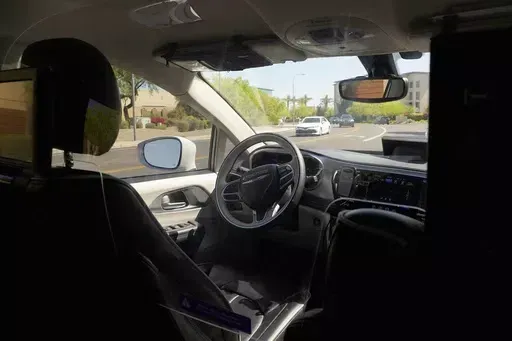 A Waymo minivan moves along a city street as an empty driver's seat and a moving steering wheel drive passengers during an autonomous vehicle ride, on April 7, 2021, in Chandler, Ariz. The U.S. government's highway safety agency has opened another investigation of automated driving systems, this time into crashes involving Waymo's self-driving vehicles. The National Highway Traffic Safety Administration posted documents detailing the probe on its website early Tuesday after getting 22 reports of