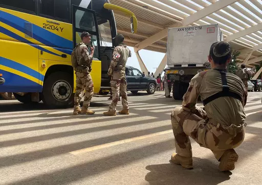 French soldiers assist mostly French nationals in a bus waiting to be airlifted back to France on a French military aircraft, at the international Airport in Niamey, Niger, Tuesday, Aug. 1, 2023. The French Foreign Ministry in Paris cited recent violence that targeted the French Embassy as one of the reasons for the evacuation. The decision comes during a deepening crisis sparked by the coup last week against Niger's democratically elected president, Mohamed Bazoum. (AP Photo/Sam Mednick)