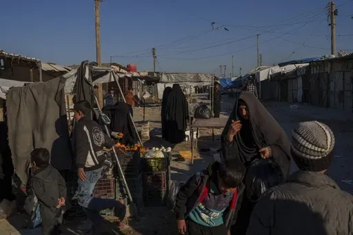 People stroll through the marketplace in the al-Hol detention camp in northeastern Syria's Hassakeh province, where tens of thousands of mostly women and children linked to the Islamic State group have been living for years, Thursday, Jan. 30, 2025. (AP Photo/Bernat Armangue)