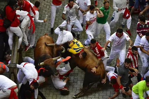 Runners fall as another is tossed by a fighting bull during the running of the bulls at the San Fermin festival in Pamplona, northern Spain, Monday, July 11, 2022. Pamplona is once again a sea of red and white as the frenzied madness of the San Fermín running of the bulls festival returns with adrenaline, emotion and passion following a two-year suspension due to the coronavirus pandemic. (AP Photo/Alvaro Barrientos, File)