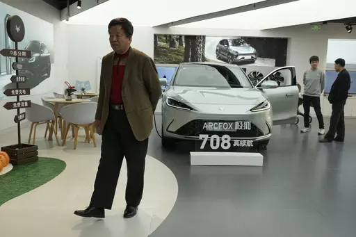 Visitors look at the Arcfox a-S, an all electric car from Chinese automaker BAIC which claims to have a 708km range on a single charge, at a show room in Beijing, Thursday, April 13, 2023. Global and Chinese automakers plan to unveil more than a dozen new electric SUVs, sedans and muscle cars this week at the Shanghai auto show, their first full-scale sales event in four years in a market that has become a workshop for developing electrics, self-driving cars and other technology. (AP Photo/Ng Ha