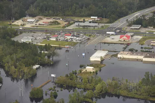 In this Monday, Sept. 24, 2018 photo, flood waters from the Neuse River cover the area a week after Hurricane Florence in Kinston, N.C. Monday Sept. 24, 2018.  Hot real estate markets have made some homeowners wary of participating in voluntary flood buyout programs, impacting efforts to move people away from flooding from rising seas, intensifying hurricanes and more frequent storms.  Flood buyout programs typically purchase flood-prone homes, raze them and turn the property into green space. (