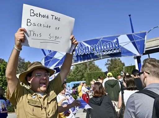 Jungle Cruise Skipper Gabriel Ramos keeps up the Jungle Cruise-style humor as he joins other Disney union members passing out buttons and ask visitors to sign a petition supporting their fight for a contract with the theme park company outside the Harbor Boulevard entrance Monday, July 1, 2024, in Anaheim, Calif. (Jeff Gritchen/The Orange County Register via AP)