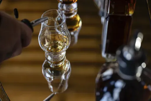 An employee pours a glass of The Bard's product in what will be a new production area at The Bard Distillery in Graham, Ky., Sunday, March 9, 2025. (AP Photo/Jon Cherry)
