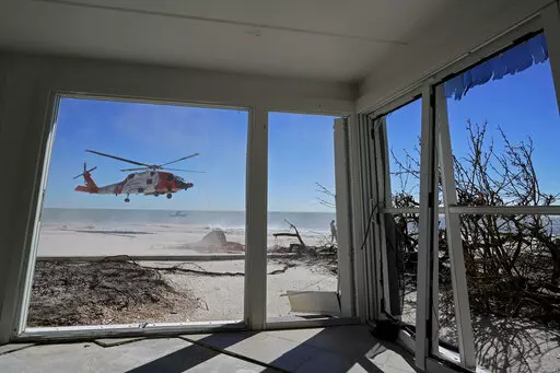 A U.S. Coast Guard helicopter takes off, seen from inside a home damaged by Hurricane Ian on Sanibel Island, Florida, Friday, Sept. 30, 2022. (AP Photo/Steve Helber)