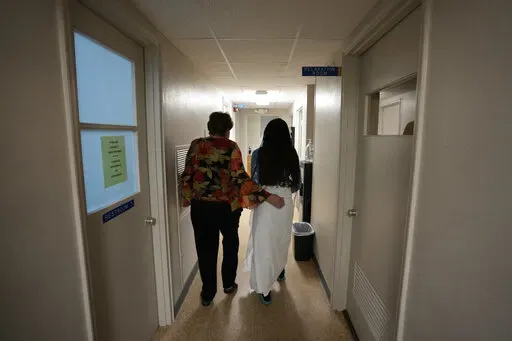 A 33-year-old mother of three from central Texas is escorted down the hall by clinic administrator Kathaleen Pittman prior to getting an abortion, Oct. 9, 2021, at Hope Medical Group for Women in Shreveport, La. Reproductive rights advocates are planning to open new abortion clinics or expand the capacity of existing ones in states without restrictive abortion laws. (AP Photo/Rebecca Blackwell, File)