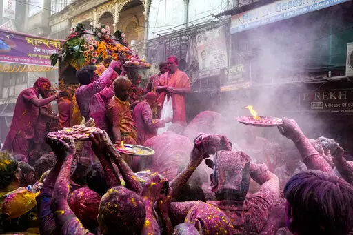 Hindu devotees with offerings make way to reach the car which carried the deity Shri Krishna during the Holi festival in Kolkata, India, Sunday, March 5, 2023. Millions of Indians on Wednesday celebrated the ''Holi" festival, dancing to the beat of drums and smearing each other with green, yellow and red colors and exchanging sweets in homes, parks and streets. Free from mask and other COVID-19 restrictions after two years, they also drenched each other with colored water. (AP Photo/Bikas Das)