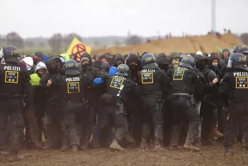 Police officers push back demonstrators on the edge of the opencast lignite mine Garzweiler at the village Luetzerath near Erkelenz, Germany, Saturday, Jan. 14, 2023. ( Oliver Berg/dpa via AP)