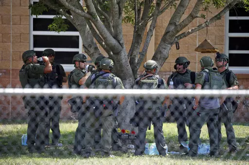 Law enforcement personnel stand outside Robb Elementary School following a shooting, May 24, 2022, in Uvalde, Texas. When the gunman arrived at the school, he hopped its fence and easily entered through an unlocked back door, police said. He holed himself up in a fourth-grade classroom where he killed the children and teachers. (AP Photo/Dario Lopez-Mills, File)