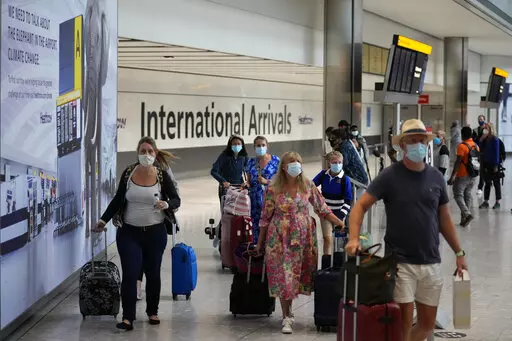 Passengers arrive at Terminal 5 of Heathrow Airport in London, Aug. 2, 2021. British Prime Minister Boris Johnson said Monday Jan. 24, 2022, his government will remove coronavirus testing requirements for vaccinated people arriving in England, news hailed by the travel industry as a big step back to normality. (AP Photo/Matt Dunham, File)