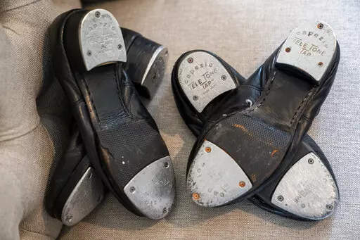 Old tap shoes rest on a chair as Gary Schaufeld describes his time as a young performer in dance competitions, Thursday, Feb. 10, 2022, at his home in Port Jefferson, N.Y. He was a teen in 2004, assisting a successful tap dancer named Danny Wallace. Schaufeld had fallen in love with tap at 7 years old, and assisting Wallace offered a chance to raise his profile and learn from one of the best. (AP Photo/John Minchillo)
