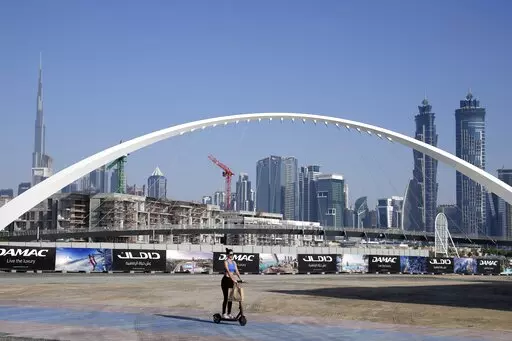 A woman rides a scooter while passing by the advertising billboards of a new residential project in Dubai, United Arab Emirates, Tuesday, Jan. 31, 2023. For the first time since a 2009 financial crisis nearly brought Dubai to its knees, several major abandoned real estate projects now show signs of life. As with its other booms, war again is driving money into Dubai and buoying its economy. This time it's Russian investors fleeing Moscow’s war on Ukraine, rather than people escaping Mideast ba