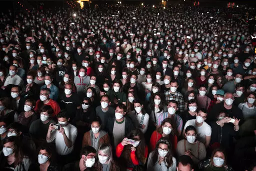People using face masks attend a music concert in Barcelona, Spain, March 27, 2021. With one of Europe's highest vaccination rates and its most pandemic-battered economies, the Spanish government is laying the groundwork to approach the virus in much the same way countries deal with flu or measles. (AP Photo/Emilio Morenatti, File)