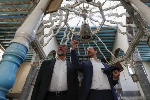 Rabbi Yusuf Hamra, left, and his son Henry take pictures as they visit the Al-Raqi synagogue in the old city of Damascus Feb. 18, 2025. The Syrian-American Jewish family returned for the first time since emigrating from Syria to the United States more than three decades ago. (AP Photo/Omar Sanadiki, File)