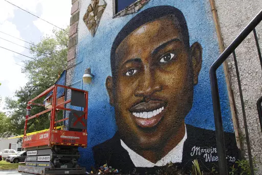 This May 17, 2020, file photo, shows a mural depicting Ahmaud Arbery in Brunswick, Ga.  Travis McMichael, the man convicted of murder for shooting Ahmaud Arbery is withdrawing his guilty plea on a federal hate crime charge.  McMichael announced his decision Friday, Feb. 4, 2022.  (AP Photo/Sarah Blake Morgan, File)