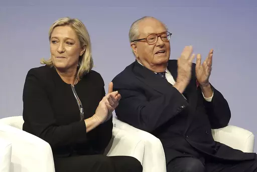 In this Saturday Nov. 29, 2014 file photo, French far-right Front National leader Marine Le Pen and her father Jean-Marie Le Pen applaud in Lyon, central France. A march against antisemitism this weekend in Paris, with the prime minister, government members, political parties and citizens in attendance, is fraught with discord over the planned presence of far-right leader Marine Le Pen. Her father and party founder Jean-Marie Le Pen has been convicted numerous times of antisemitism and racism. (