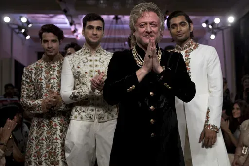Fashion designer Rohit Bal, foreground, acknowledges the applause next to models wearing his creations at the end of his show at the Couture Week 2016 in New Delhi, India, Sunday, July 24, 2016. (AP Photo/Tsering Topgyal, File)