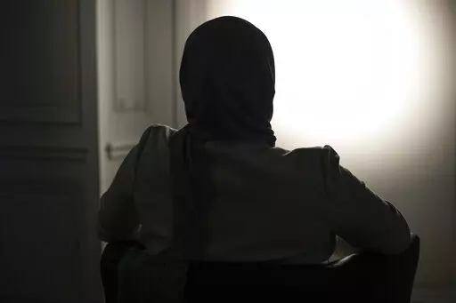 The sister, who refused to show and identify, of a woman imprisoned in Turkey is silhouetted during an interview with The Associated Press in Paris, Wednesday, Feb. 16, 2022. Shatz and a team of European lawyers filed a case against Greece at the European Court of Human Rights on behalf of a 32-year-old French woman who accuses the Hellenic country of forcibly pushing her back across the border from Greece to Turkey, where she claims she is a victim of political persecution. The woman, who is al