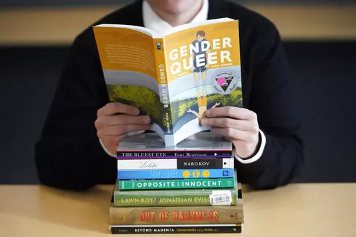 Amanda Darrow, director of youth, family and education programs at the Utah Pride Center, poses with books on Dec. 16, 2021, that have been the subject of complaints from parents in Salt Lake City. (AP Photo/Rick Bowmer, File)