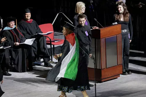 A graduate twirls with her Palestinian flag cape during the Emerson College commencement ceremony at Boston University's Agganis Arena, Sunday, May 12, 2024, in Boston. Many students verbally protested throughout the ceremony. (Pat Greenhouse/The Boston Globe via AP)
