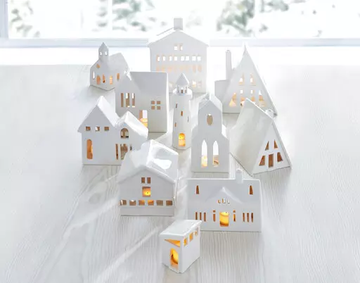 This image provided by Crate & Barrel shows their collection of white ceramic buildings. Crate & Barrel's collection includes alpine homes and hotels as well as midcentury split levels and ranch homes. Add a tealight for a welcoming glow. (Crate & Barrel via AP)