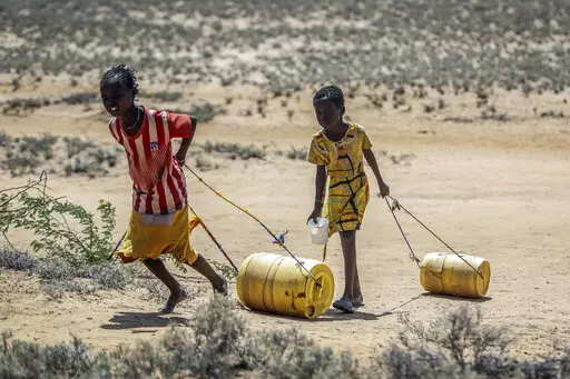 Young girls pull containers of water during a drought as they return to their huts from a well in the village of Lomoputh in northern Kenya on, May 12, 2022. Better climate-related research and early weather warning systems are needed as extreme weather — from cyclones to drought — continues to inflict the African continent, said the Sudanese billionaire and philanthropist Mo Ibrahim, who heads up his own foundation. (AP Photo/Brian Inganga, File)