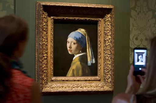 FILE- Visitors take pictures of Johannes Vermeer's Girl with a Pearl Earring (approx. 1665) during a preview for the press of the renovated Mauritshuis in The Hague, Netherlands, June 20, 2014. The Vermeer masterpiece “Girl with a Pearl Earring” has become the latest artwork targetted by climate activists in a protest at the Mauritshuis museum in The Hague on Thursday, Oct. 27, 2022. The museum did not immediately return calls and emails for comment after a video of the protest was posted on