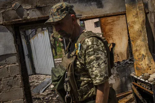Commander of an artillery unit of the Ukrainian army, Mykhailo Strebizh, center, inside a destroyed house due to shelling in a village near the frontline in the Donetsk oblast region, eastern Ukraine, Thursday, June 2, 2022. (AP Photo/Bernat Armangue, File)