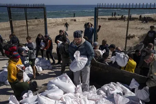 Volunteers load a vehicle with sandbags to defend the city, in Odesa, southern Ukraine, on March 23, 2022. The Black Sea port is mining its beaches and rushing to defend itself from a Mariupol-style fate. (AP Photo/Petros Giannakouris, File)