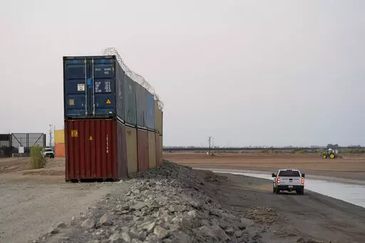Border Patrol agents patrol along a line of shipping containers stacked near the border on Aug. 23, 2022, near Yuma, Ariz. The Cocopah Indian Tribe is welcoming the federal government's call for the state of Arizona to remove a series of double-stacked shipping containers placed along the U.S.-Mexico border near the desert city of Yuma, saying they are unauthorized and violate U.S. law. (AP Photo/Gregory Bull, File)