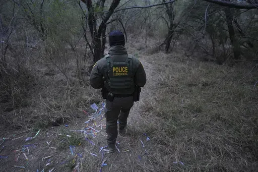 A border patrol agent walks along a trail littered with bracelets used by human smuggling groups near the Rio Grande at the U.S.-Mexico border, Thursday, Feb. 13, 2025, in McAllen, Texas. (AP Photo/Eric Gay)