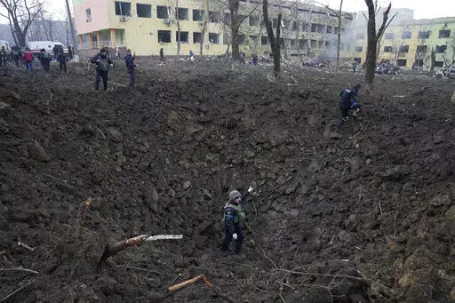 Ukrainian soldiers and emergency employees work outside a maternity hospital damaged by shelling in Mariupol, Ukraine, Wednesday, March 9, 2022. An Associated Press team of journalists was in Mariupol the day of the airstrike and raced to the scene. Their images prompted a massive Russian misinformation campaign that continues to this day. (AP Photo/Evgeniy Maloletka, File)