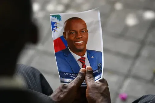 A person holds a photo of the late Haitian President Jovenel Moise during his memorial ceremony at the National Pantheon Museum in Port-au-Prince, Haiti, July 20, 2021. Haiti's National Police said Saturday, Jan. 15, 2022, that former Sen. John Joel Joseph, sought in the July 7 killing of Moise, has been arrested in Jamaica. (AP Photo/Matias Delacroix)