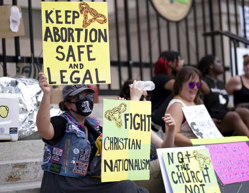 A small group, including Stephanie Batchelor, left, sits on the steps of the Georgia state Capitol protesting the overturning of Roe v. Wade on June 26, 2022. The Georgia Supreme Court on Wednesday, Nov. 23, reinstated the state’s ban on abortions after roughly six weeks of pregnancy. (AP Photo/Ben Gray, File)