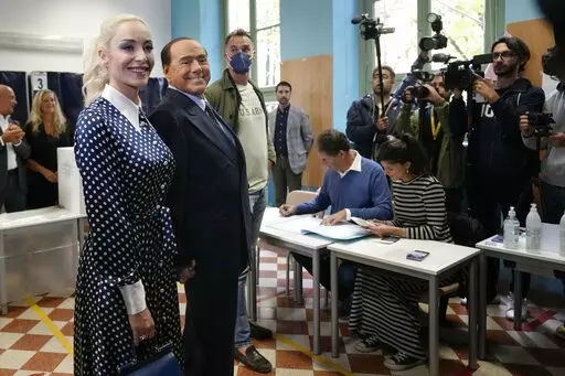 Silvio Berlusconi, leader of center-right, populist Forza Italia is flanked by his partner Marta Fascina, after casting his ballot at a polling station in Milan, Italy, Sunday, Sept. 25, 2022, in Milan, Italy.  Just in time to celebrate his 86th birthday, Italy’s former premier Silvio Berlusconi is making his return to Italy's parliament, winning a seat in the Senate nearly a decade after being banned from public office over a tax fraud conviction. (AP Photo/Antonio Calanni, File)